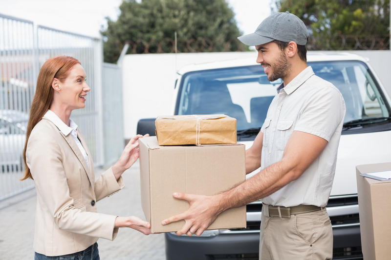 Delivery driver passing parcels to happy customer outside the warehouse